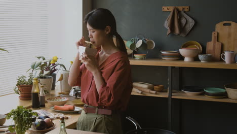 young woman eating take-out food in kitchen