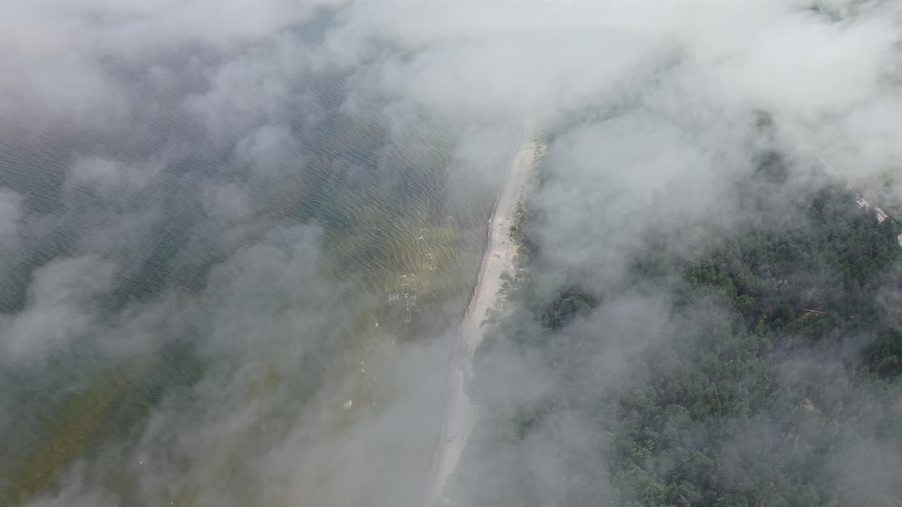 Aerial view of a river in the middle of the forest partly covered by clouds