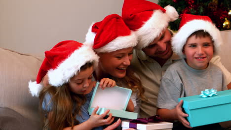 happy young family opening christmas presents on couch