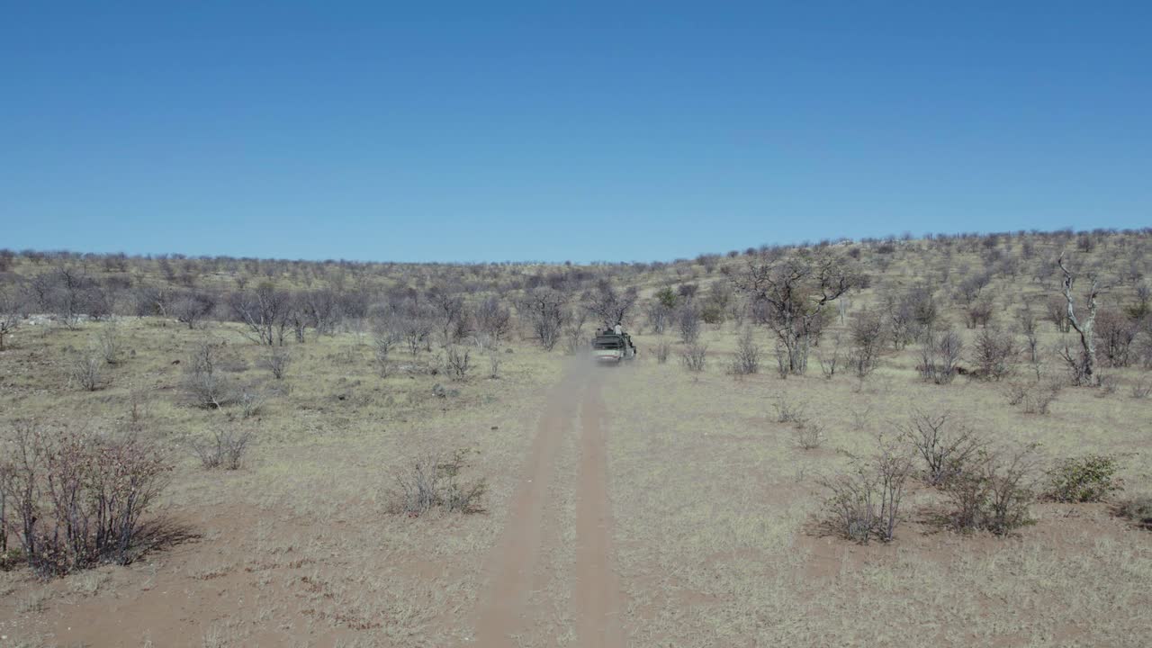 공중 추적 샷 - 관광객을 운전하는 아프리카 오픈 탑 사파리 차량