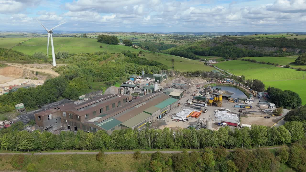 Scenic aerial drone view of wind turbines and factories with rolling green hills in Derbyshire Dales United Kingdom