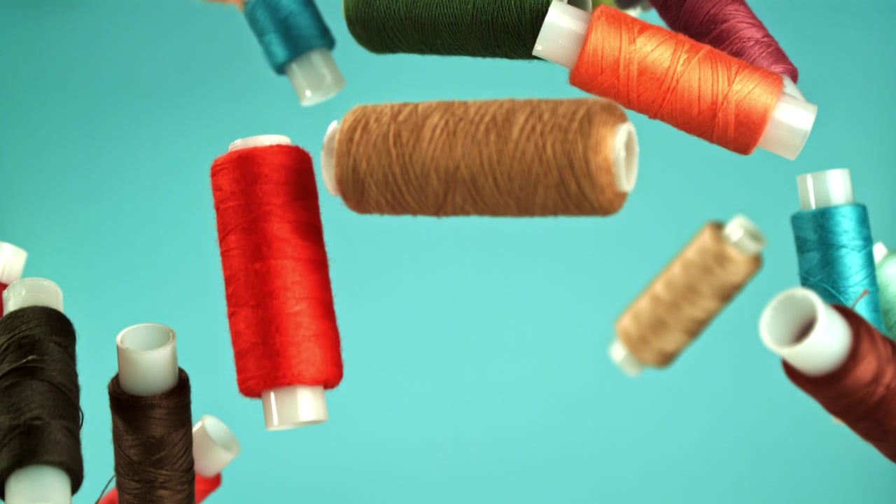 Colorful Spools of Thread Falling and Floating on a Blue Background
