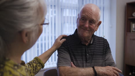 an elderly man is comforted by a woman who places her hand on his shoulder