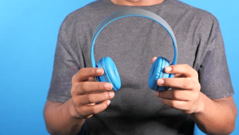 person holding blue headphones