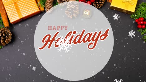 animation of happy holidays text over snow falling, christmas decoration and presents on table