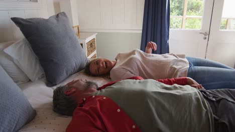 feliz pareja caucásica madura acostada en la cama en una habitación de hotel