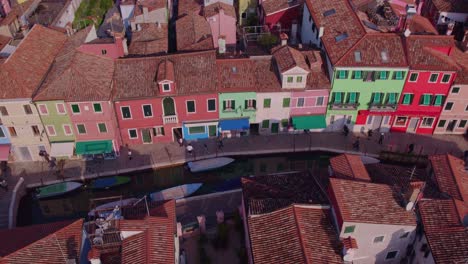 Casas-Coloridas-Y-Vibrantes-En-Burano-Con-Un-Pequeño-Canal-Y-Gente-Caminando,-Aérea