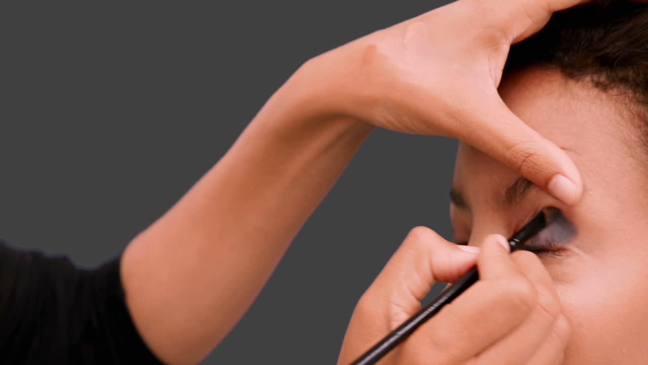 artista de maquillaje poniendo sombra de ojos en la cara de los modelos