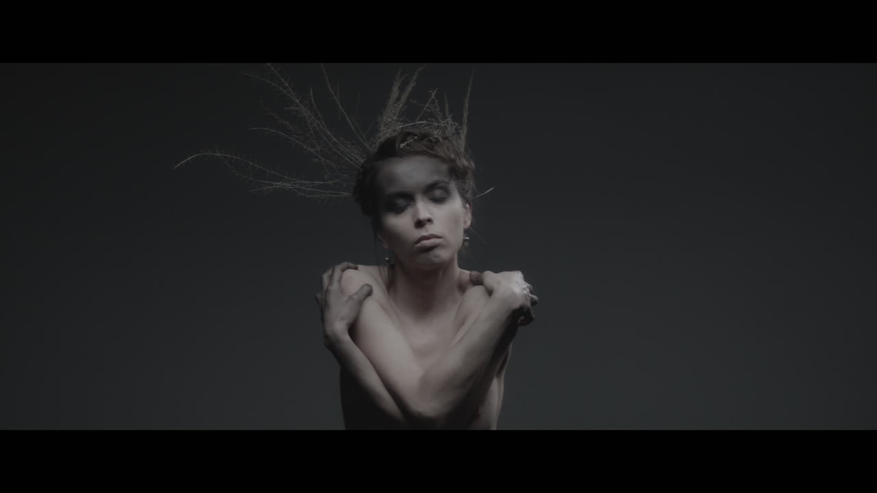 A woman dressed as mother nature moves slowly in a dance-like motion