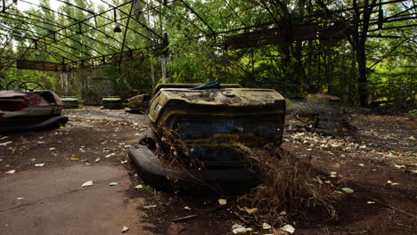 Overgrown-and-contaminated-bumper-cars-in-Pripyat-on-sunny-day,-pan-right