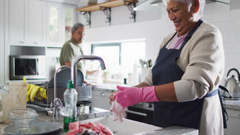 Happy-senior-biracial-couple-washing-dishes-in-kitchen