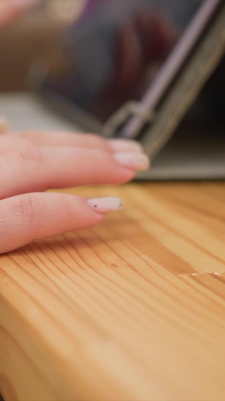 Close up of woman hand with manicured nails. Hand remains steady emphasizing natural skin texture and nail design. Soft lighting highlights wood grain patterns and subtle shadows