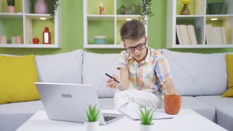 Little-boy-dreaming-of-becoming-a-businessman.-He-works-at-home-on-a-laptop.