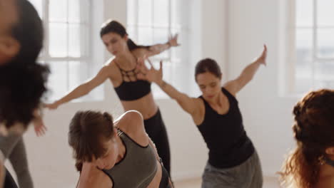 hermosa mujer caucásica de yoga practicando meditación en pose traingle con un grupo de mujeres multirraciales disfrutando de un estilo de vida saludable haciendo ejercicio en un gimnasio al amanecer.