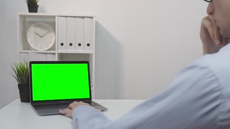 un hombre usando una computadora portátil con una pantalla verde
