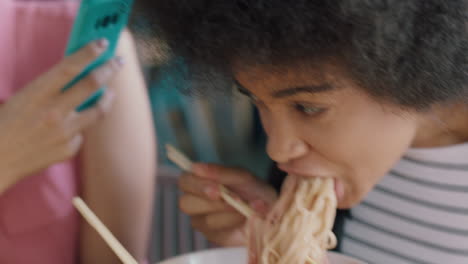 beautiful african american woman eating spaghetti at restaurant with friend using smartphone taking photo having fun sharing weekend together on social media 4k