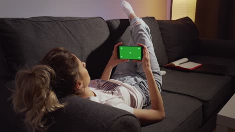 woman staying home and watching phone green screen.