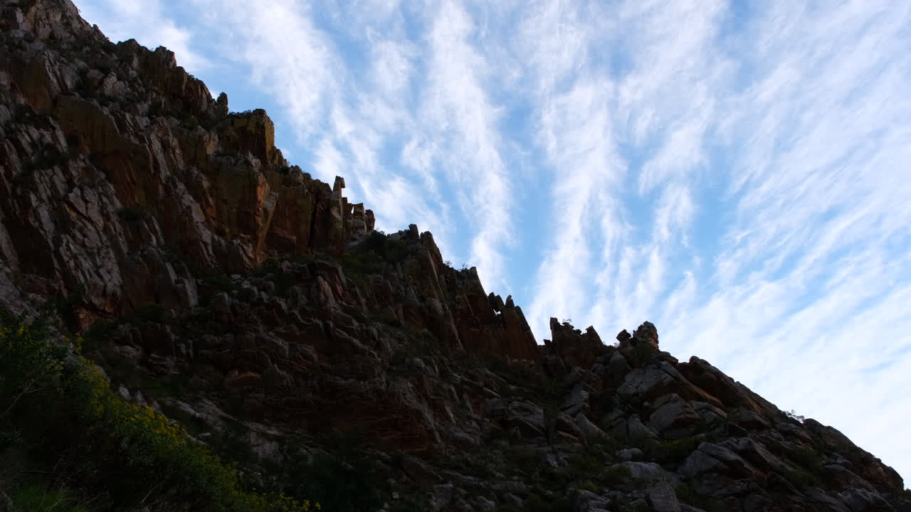 Rugged rocky mountain ridge contrasting against blue sky with wispy clouds