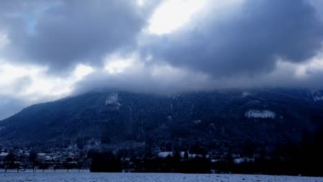 Timelapse-of-a-mountain,-homes-in-the-valley,-and-bursting-clouds