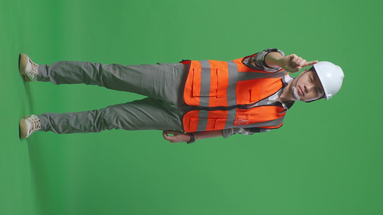 Full Body Of Asian Male Engineer With Safety Helmet Disapproving With No Index Finger Sign While Standing In The Green Screen Background Studio
