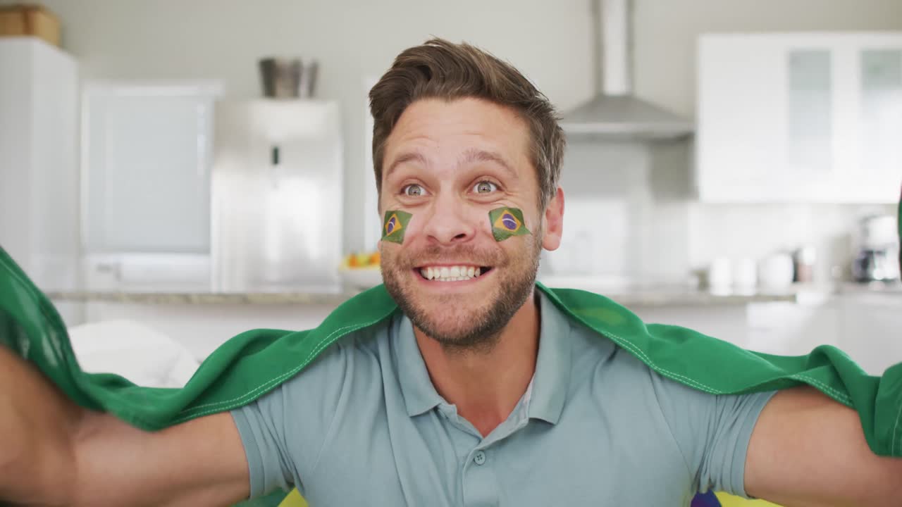 Video of excited caucasian man with flag of brazil watching match in tv