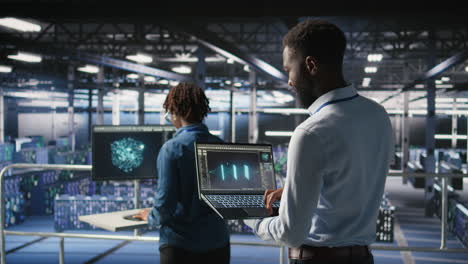 engineers in data center reviewing large language model visualizations on laptop