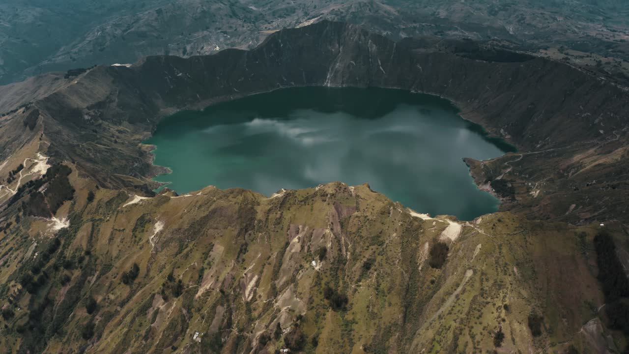 Ripresa aerea in tilt-up del Lago del cratere Quilotoa all'interno di un vulcano durante una giornata nuvolosa nelle Ande, Ecuador