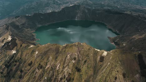 aerial tilt up shot of quilotoa crater lake inside volcano during cloudy day in andes,ecuador