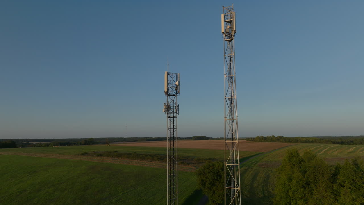 해가 뜨는 동안 농지 한가운데에 있는 두 개의 라디오 타워, 위로 기울어지는 공중  ⁇ 도 돌리