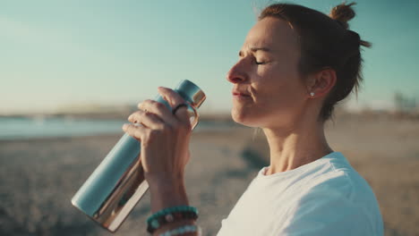 sportswoman drinking water on the beach.