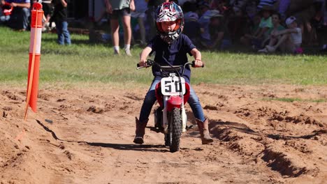 child on dirt bike performs slalom in motocross event