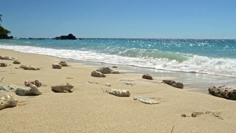 Waves-crashing-on-rocks-on-tropical-sandy-beach,-Nosy-Be,-Nosy-Fanihy,-Madagaskar,-Africa