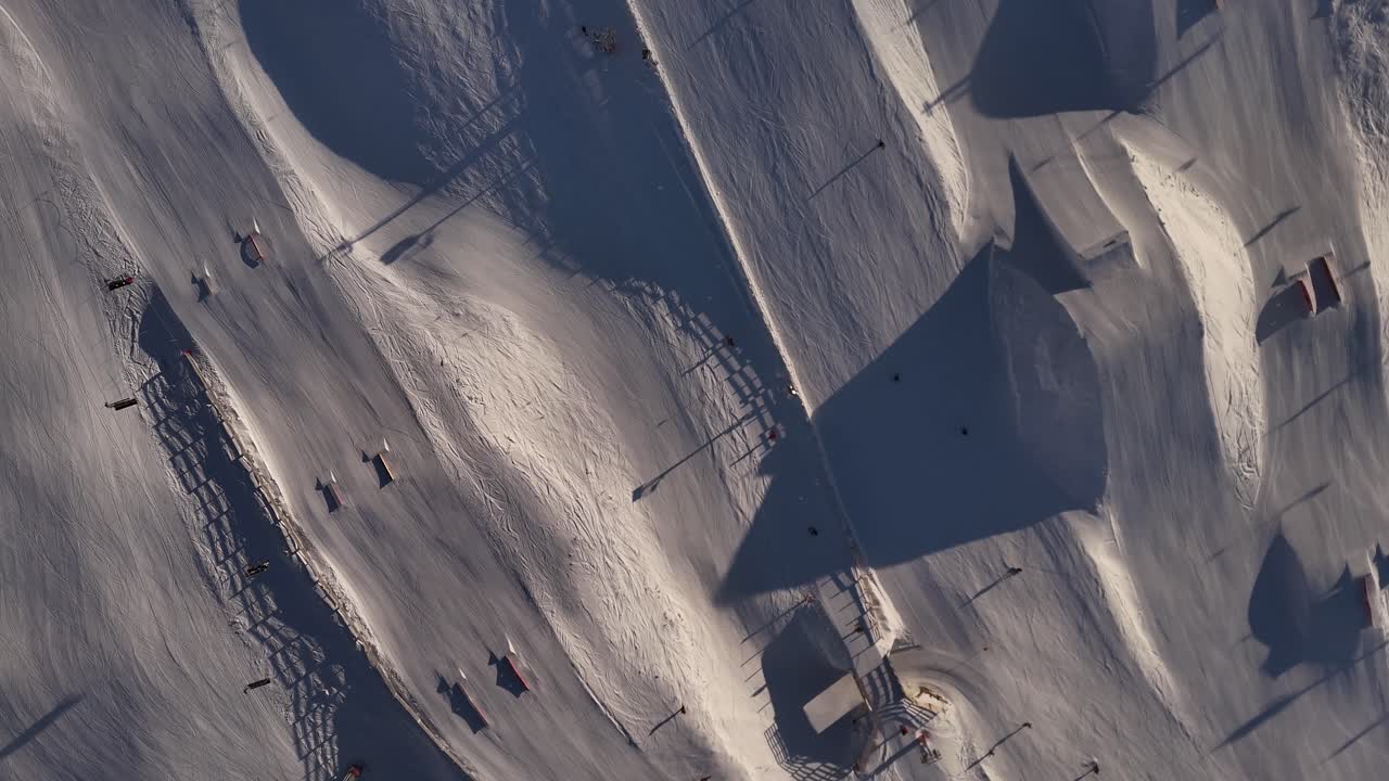 Dynamic 4K 60fps aerial footage captures skiers enjoying a day on the slopes at Cardrona Ski Resort, New Zealand. This clip showcases the popular winter sport in a beautiful alpine setting