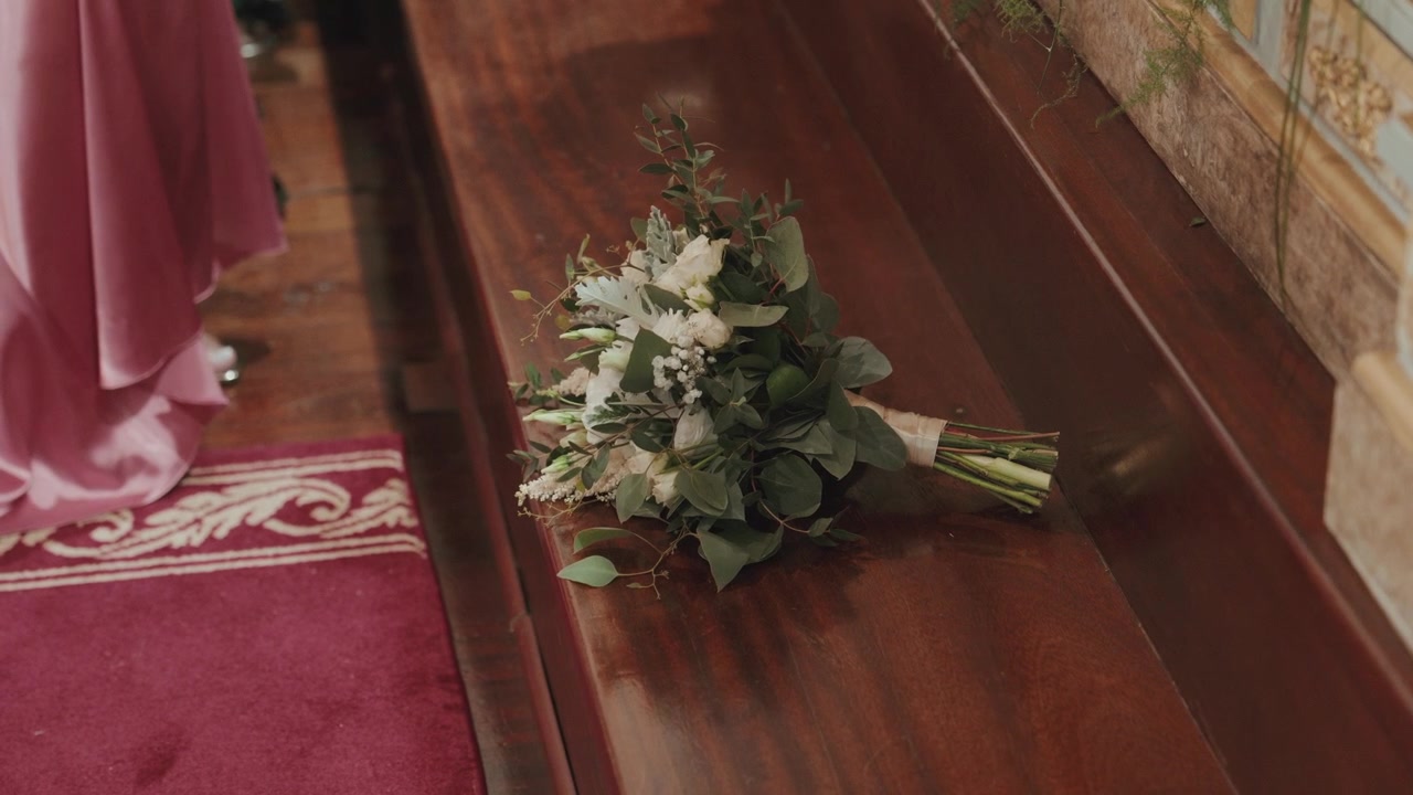 Bouquet di fiori bianchi con verde adagiato su una panca di legno della chiesa