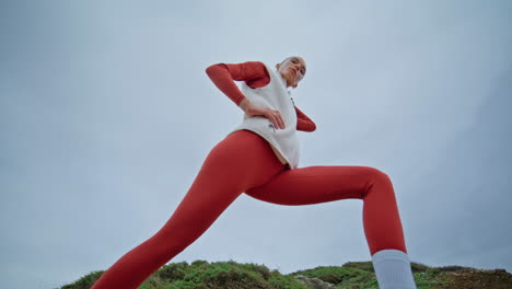 fit athlete warming up gloomy sky bottom view. slim sporty woman training