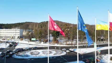 aerial slow motion of waving polish, european and flag of gdansk during snowy winter day with cars in background