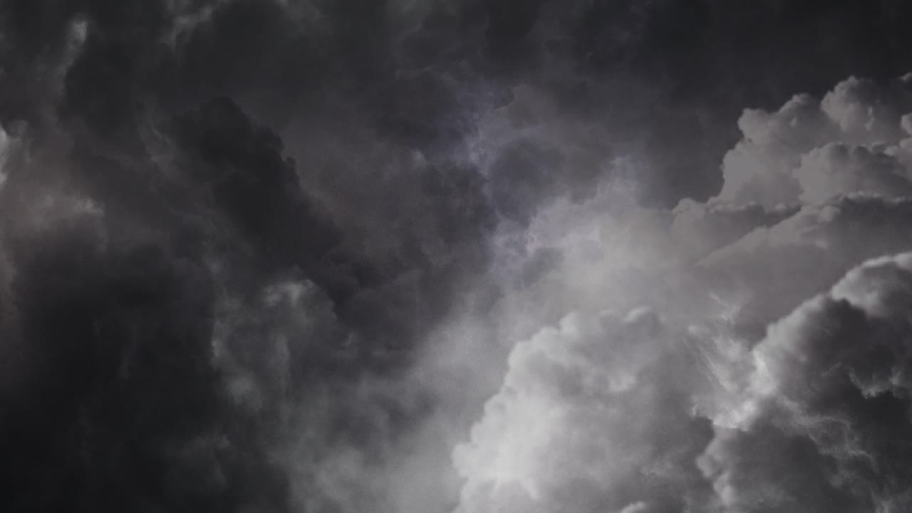 Lightning flashes among thick dark cumulonimbus clouds in the sky