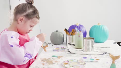 niña pequeña pintando colas de sirena y conchas marinas con pintura acrílica