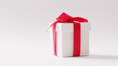 video of side view of white gift box tied with red ribbon, on white background with copy space