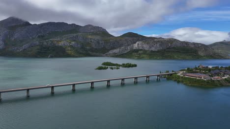 aerial view of a bridge over a lake surrounded by mountains