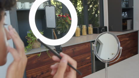 applying makeup, person using smartphone with ring light in modern kitchen