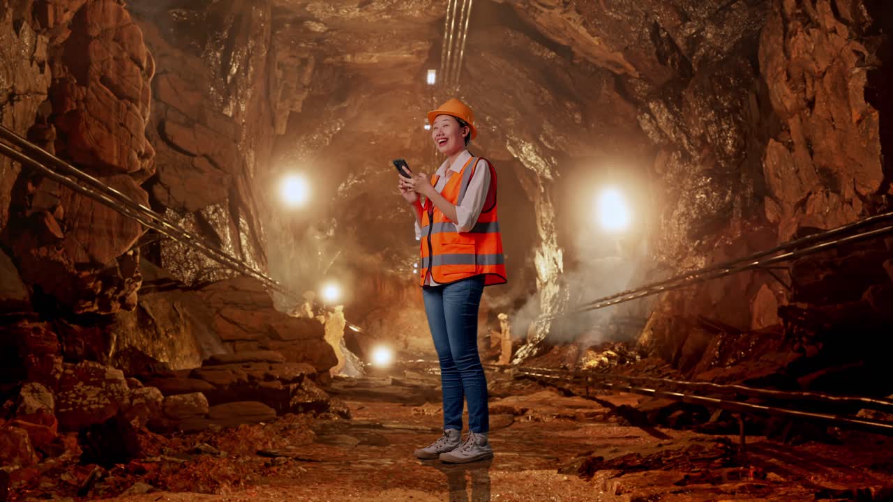 Female Miner Using Smartphone in a Mine Tunnel
