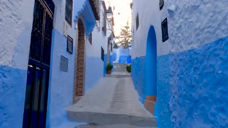 pov walking up narrow empty street in chefchaouen with blue coloured walls on either side