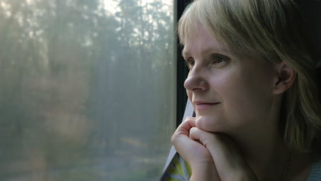 portrait of a young woman traveling in a train looking out the window the sun's rays illuminate her