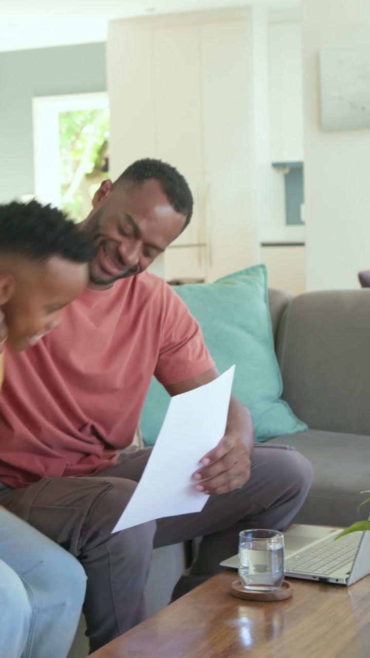 Video verticale: Figlio che entra con lo zaino mostrando la pagella per ricevere elogi, papà in rosa che legge a casa