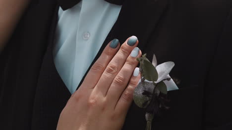 lady strokes chest of groom in tuxedo with small boutonniere