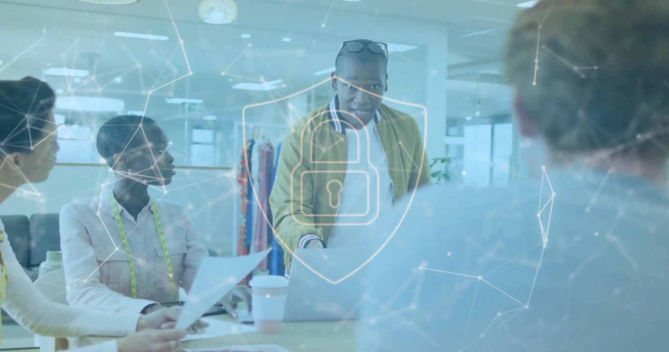 Animation of connected dots and padlock in shield, diverse designers sharing ideas in office