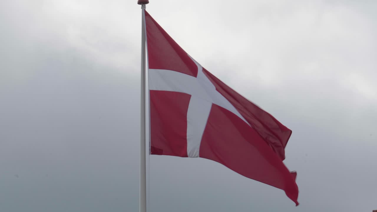 Dannebrog vajende i vinden med overskyet himmel i Aabenraa, Danmark