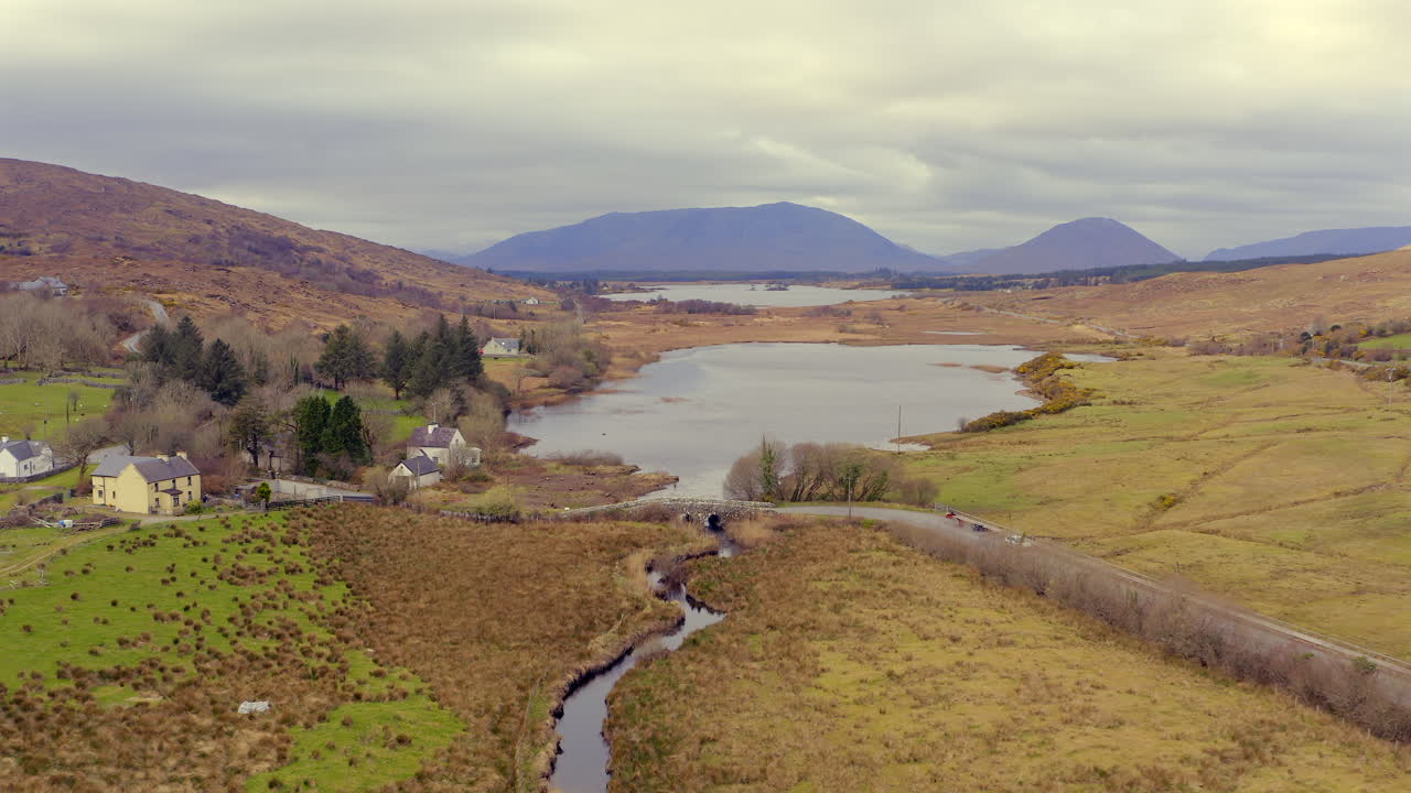 Retreating drone shot of Quiet Man Bridge revealing expansive Connemara landscape