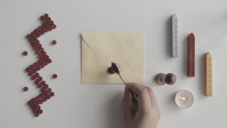 close-up on hand putting melted red wax on letter envelope